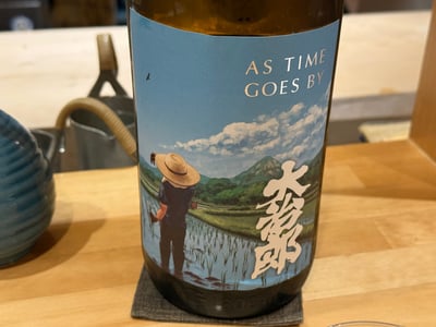 カウンターに置いた大那 AS TIME GOES BY の一升瓶。田植えの絵が描いてある。
