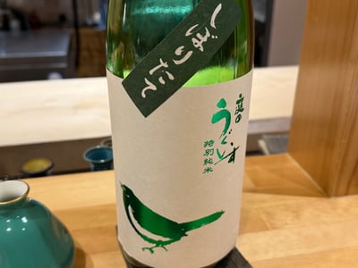 カウンターに置いた庭のうぐいす特別純米の一升瓶。緑の肩貼りに「しぼりたて」とある。