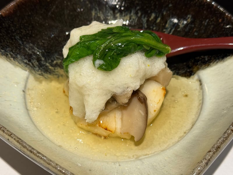 黒い角鉢に、すりおろした蕪をかぶせたクエの蒸し物。きのこと青菜、淡い餡。