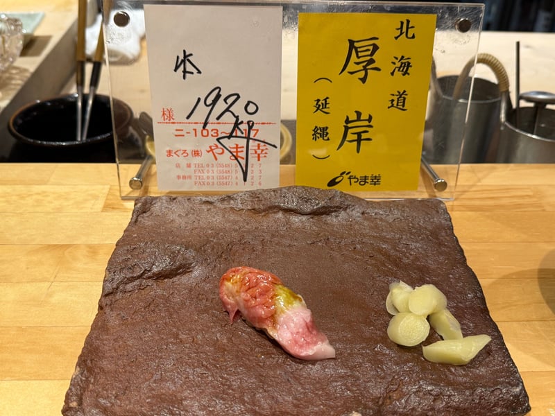 カウンターに立てた、やま幸の荷札。北海道厚岸、延縄、本まぐろとある。手前に握りとガリ。