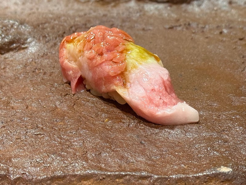 茶色い石の台にのった、脂の白い筋が入った本マグロの握り。