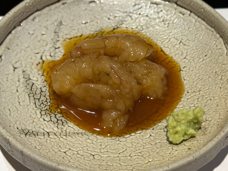 粉引の鉢に、茶色いタレをまとったシラサエビの剥き身。脇にわさび。