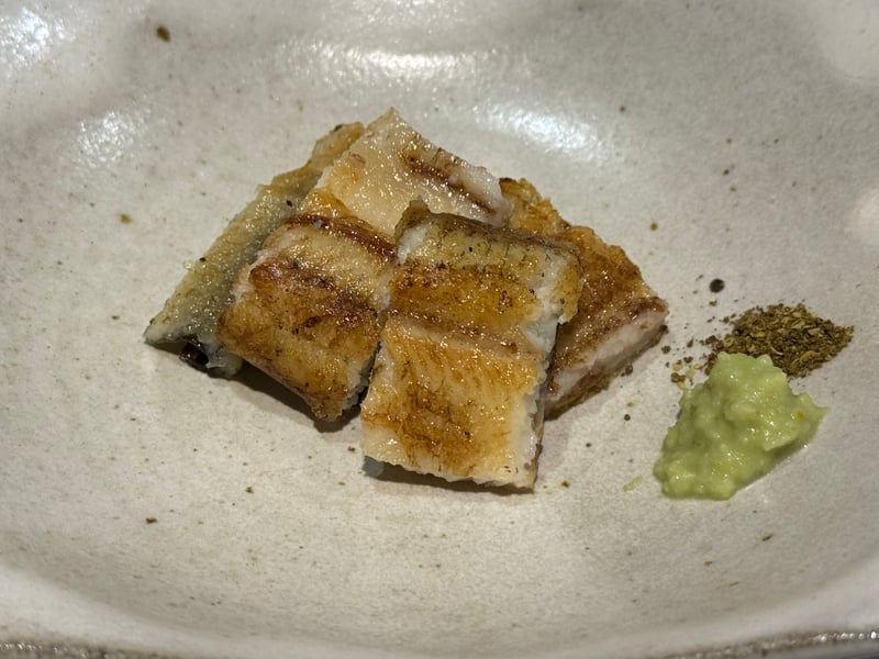 白い器に、四切れに切った鰻の白焼き。わさびと粉の山椒を添えて。
