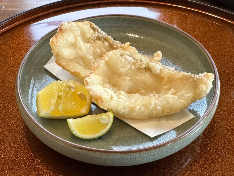 丸皿に盛られた白身魚の揚げ物二切れと二種の柑橘