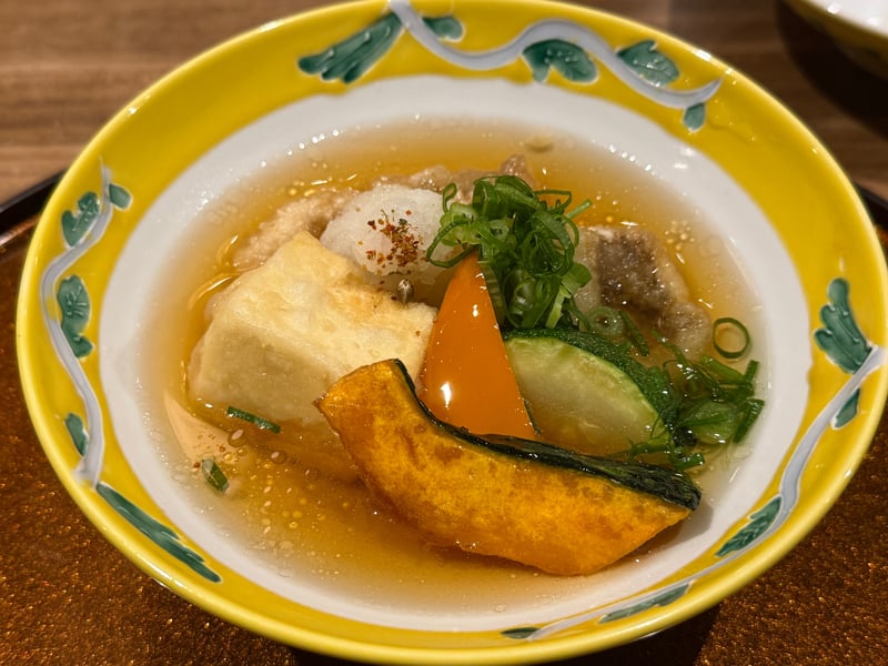 黄色い縁の鉢に張った出汁の揚げ出し豆腐、かぼちゃとズッキーニ