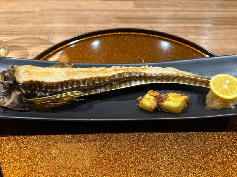 黒い長皿にのった八角の姿焼き、檸檬とじゃがいも添え