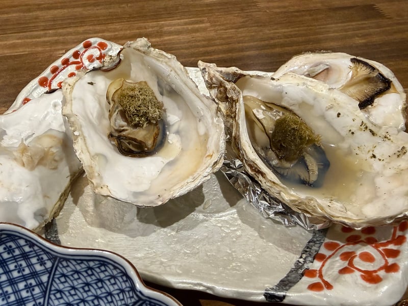 殻ごと焼いて青みをのせた牡蠣が二つ