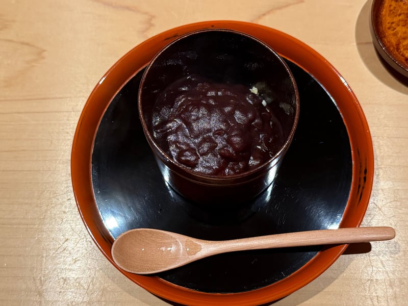 漆の椀に入った粟ぜんざいと、木の匙。