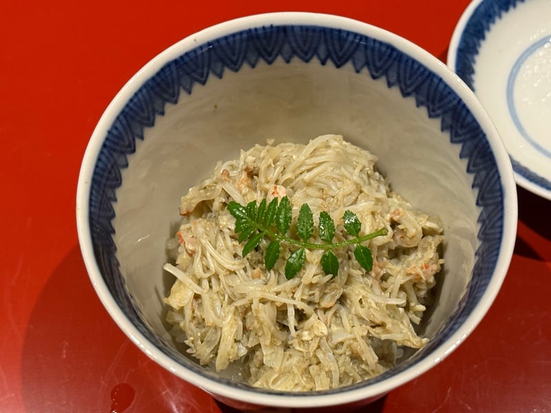 染付の小丼に、ほぐした蟹と蟹味噌をのせた餅米。上に木の芽。