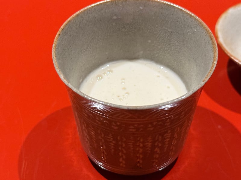 飴釉の筒茶碗に張った、白子のすりながし。細かい泡が立っている。