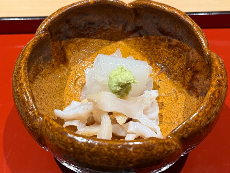 飴釉の輪花鉢に、白いヤリイカとバイ貝の切り身。上にわさび。