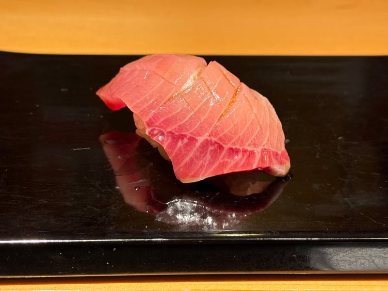 脂の差したぶりの握り。台に濃い色のタレがたまっている