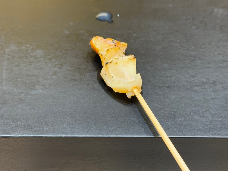 黒いつけ台に、串に刺して焼いたバイ貝