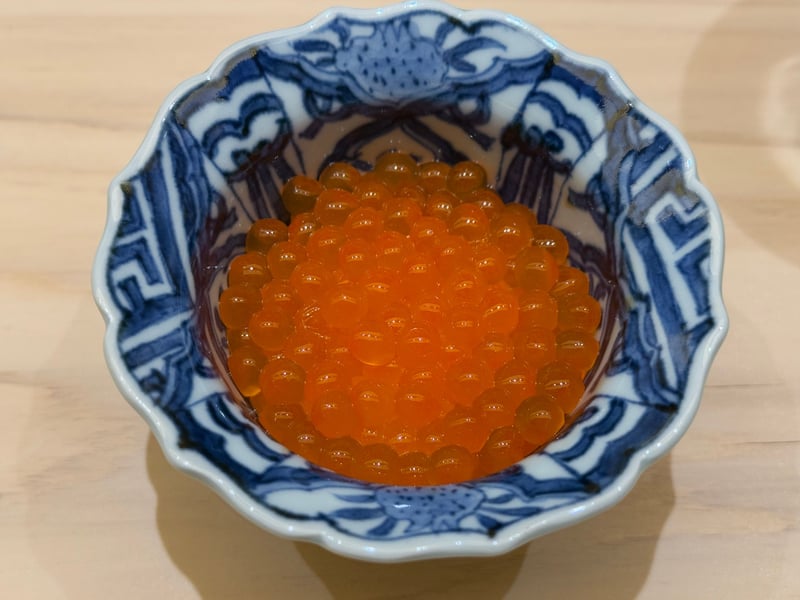 蟹を染めた染付の鉢に、醤油をまとった生イクラ