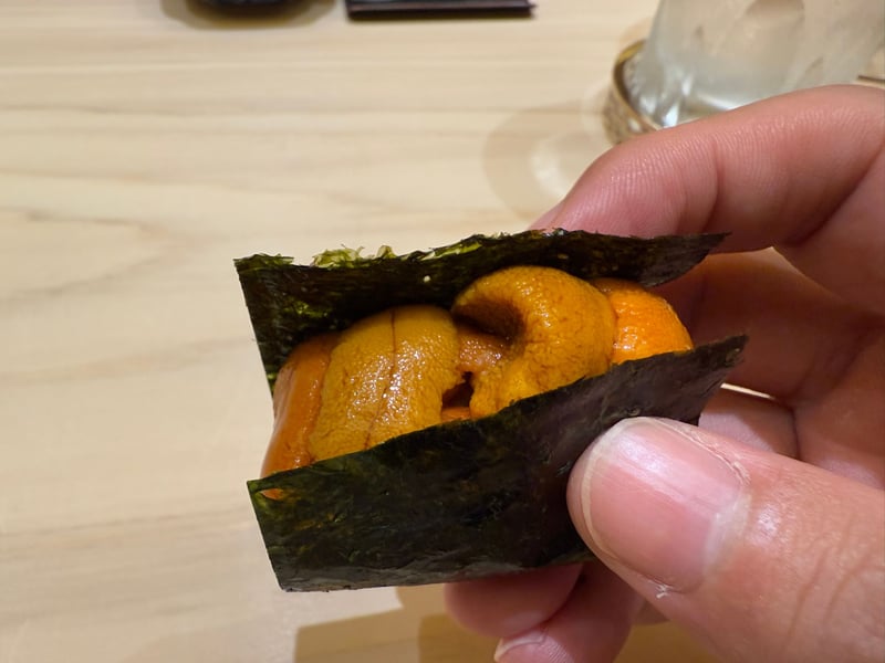 海苔で巻いたバフンウニの手巻きを手に持って