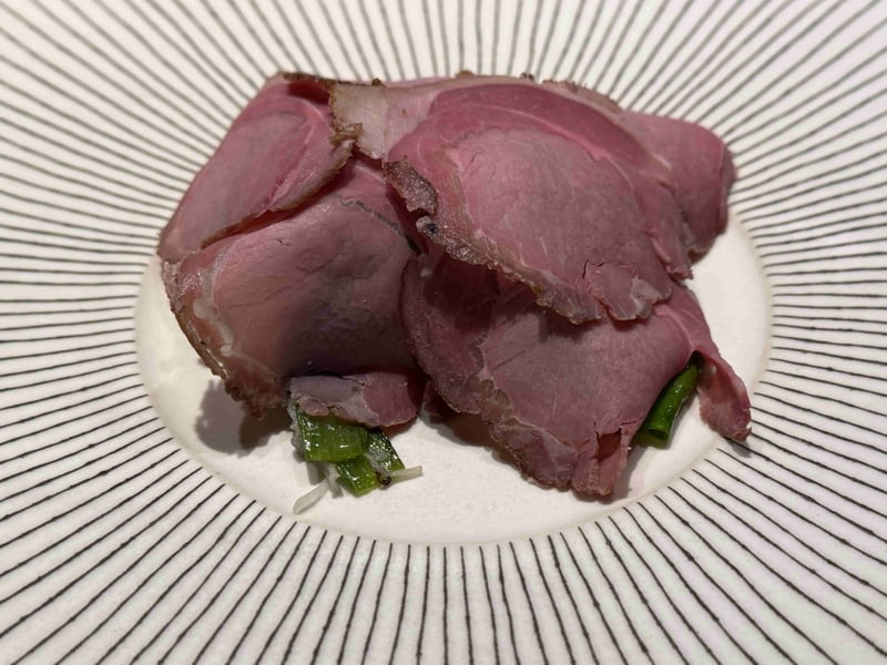 薄く切った淡い桃色の猪肉を、青菜にかぶせるように盛ってある