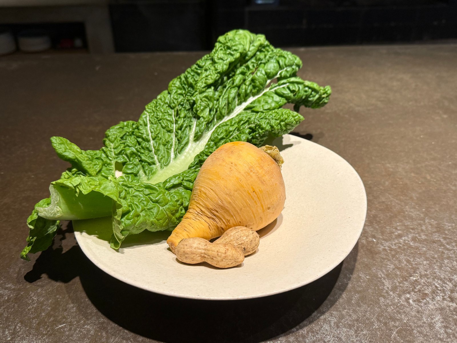 白い皿に、根の形のまま黄金かぶ、殻付きの落花生、ちぢれた葉のかつお菜