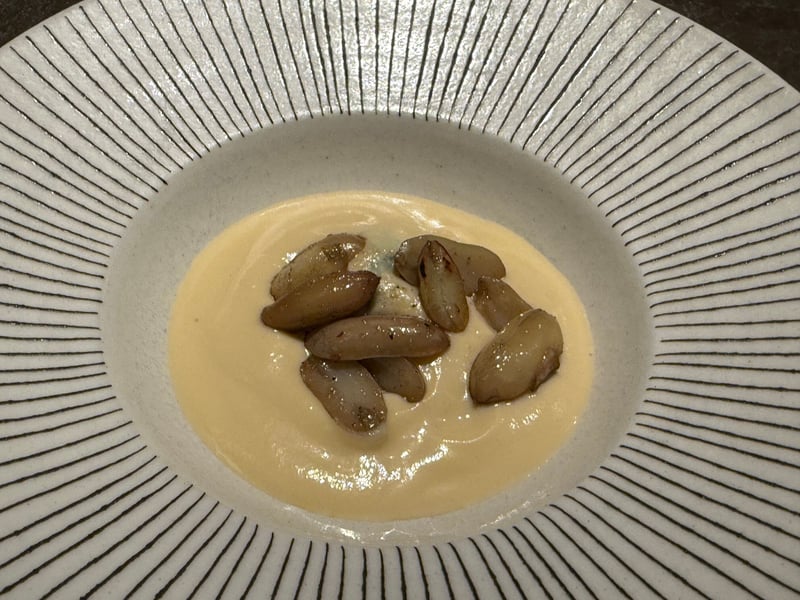 浅い皿のクリーム色のピュレに、焼いた落花生の粒が並ぶ