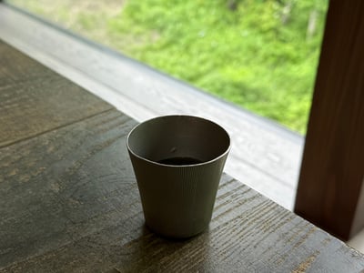 窓辺の筒形の器に入った、濃い色の飲みもの