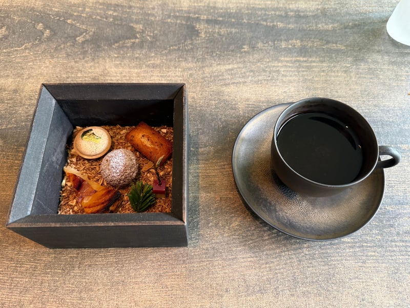 木箱に並んだ小菓子と、黒いカップのコーヒー