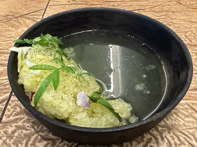黒い器に盛ったゆうかメロンのスープと、凍らせたメロンとハーブ