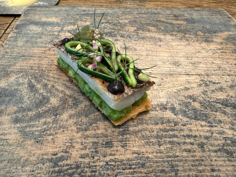 炭火で焼いた太刀魚を重ねた一皿。上にきゅうりとディル、つるむらさきの花
