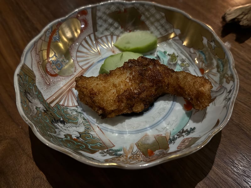金彩の鉢に、揚げた佐久鯉が一切れ。青いソースを2つ添える