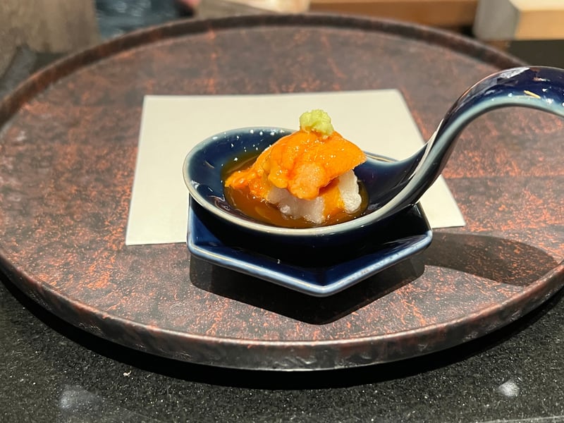 藍の匙形の器に、胡麻豆腐と雲丹、卵黄のソース。頂にわさびをひと粒