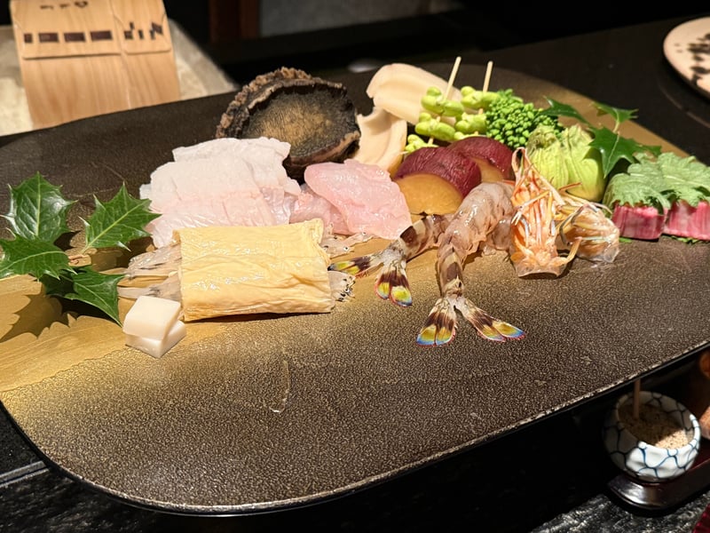 この日の食材を並べた板。鮑、白身、湯葉、生の車海老、蓮根、そら豆の串、菜の花、蕗のとう