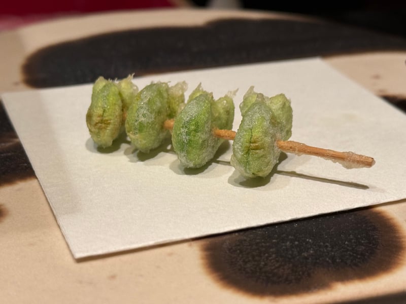 串に刺して揚げたそら豆が四粒、和紙の上に