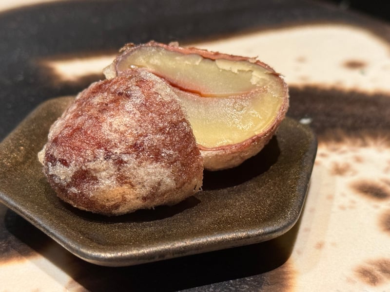 小皿にのせた揚げた栗。一つは渋皮ごと、一つは割って黄色い実が見えている