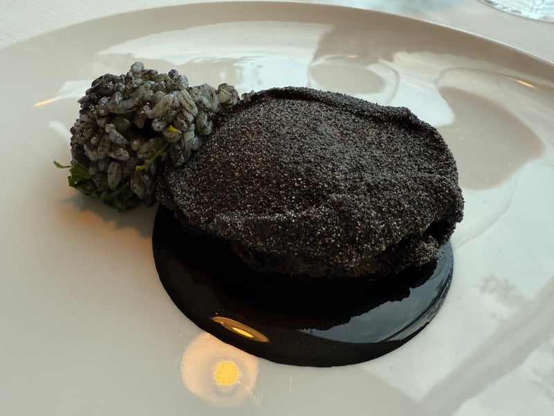 イカ墨ソースで黒く仕上げた蝦夷鮑のソテーと黒いリゾット