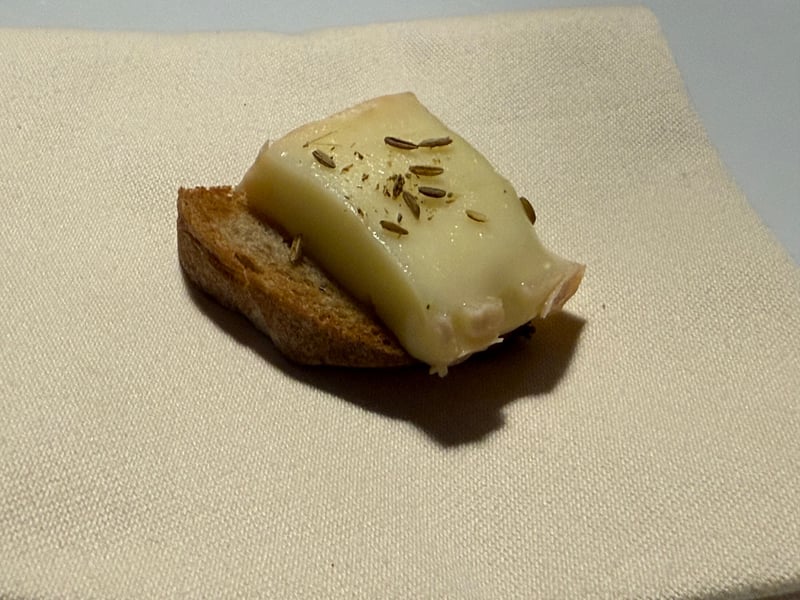 小さなトーストにのせたチーズ。表面に細長い種が散らしてある