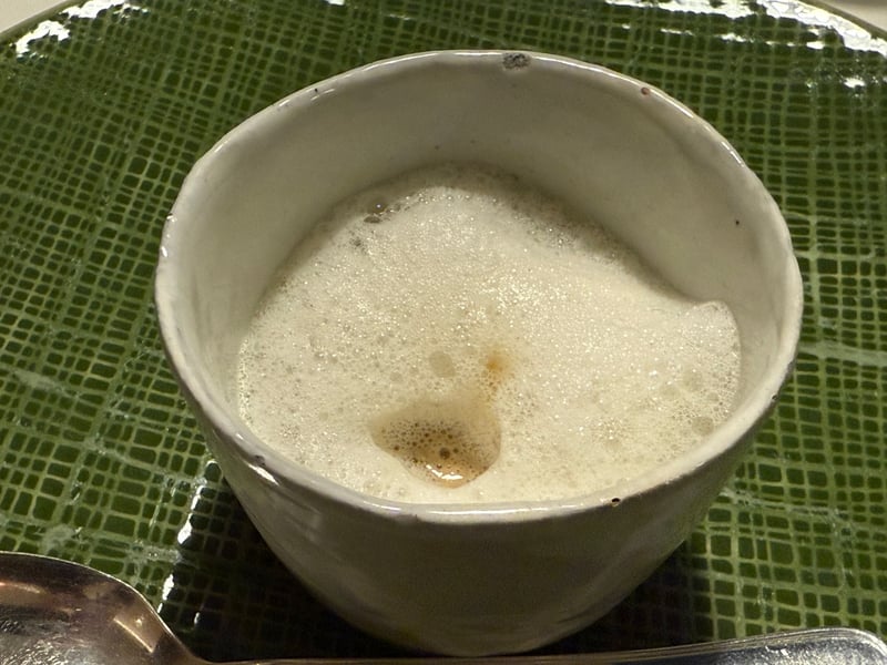 緑の釉薬の皿に載った白い碗。茸のスープの上に細かい泡が立ててある