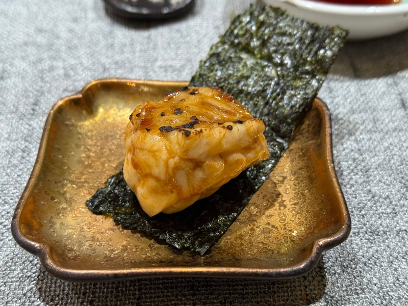 金色の小皿に敷いた海苔の上に、タレを塗って炙ったマダコの厚い一片