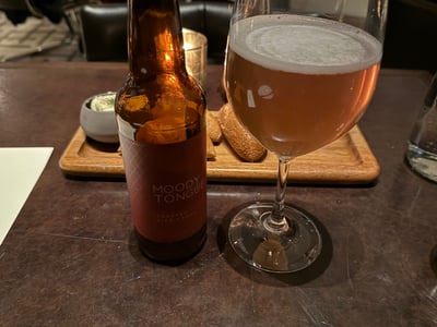 Moody Tongue のトースティッド・ライス・ラガー。瓶とワイングラス、奥にパン