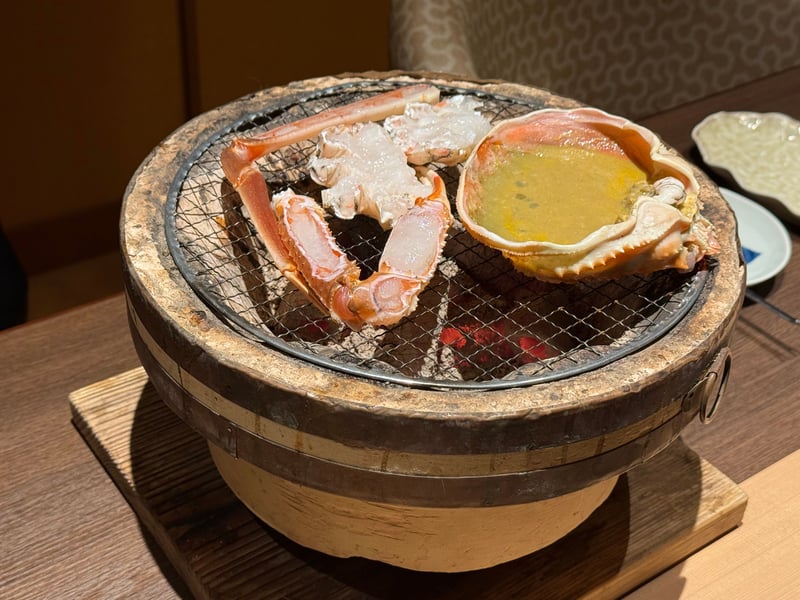 七輪の網の上で焼かれる加能蟹の脚と、甲羅に入った蟹味噌