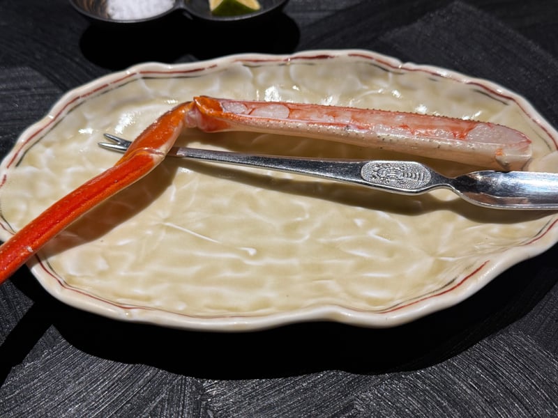 焼き上がった加能蟹の脚を皿に取り、蟹用のフォークを添える