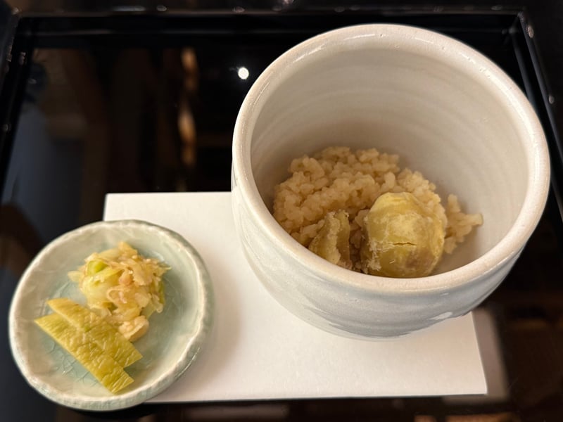 白い器の栗ごはんに大きな栗。左に香の物の小皿
