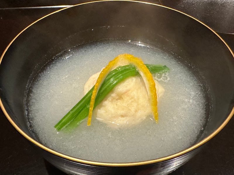 黒に金縁の椀。白いみぞれ仕立ての中に蟹しんじょう、柚子の皮と青菜