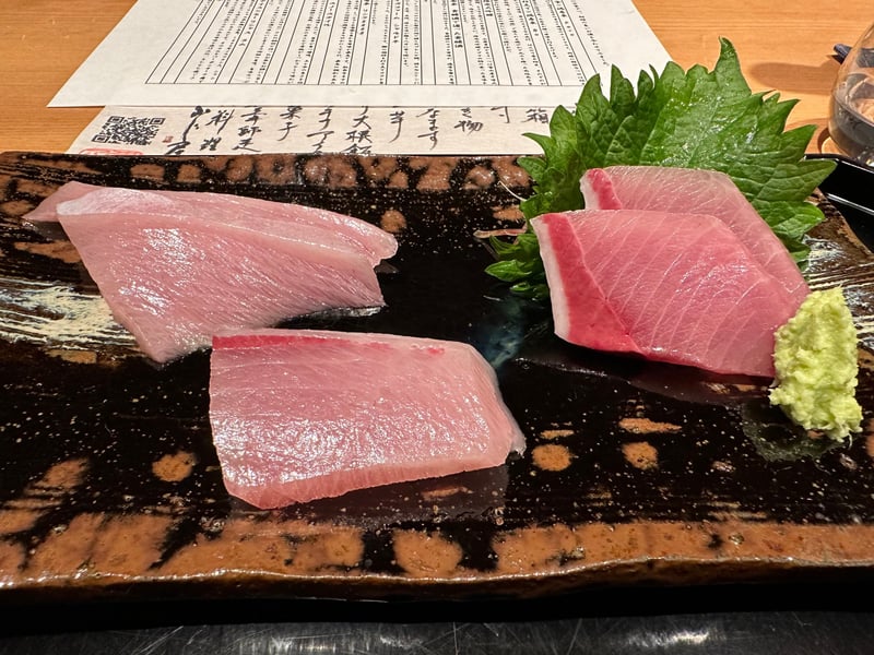 飴釉の板皿に寒ぶりの造りが三種。脂の白い層がはっきり見える