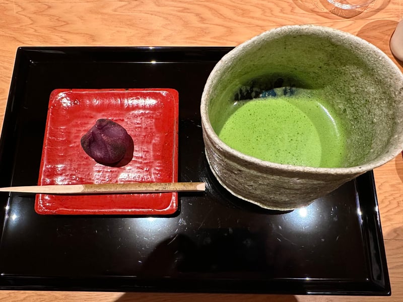 赤い角皿にのった紫芋の和菓子。隣に抹茶の碗