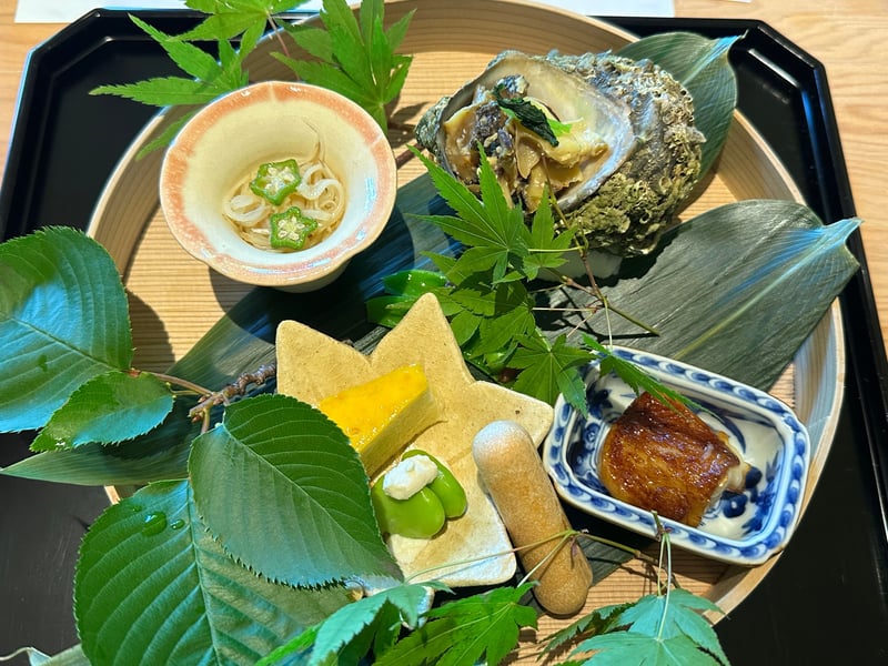 青葉をあしらった丸盆に7種の八寸