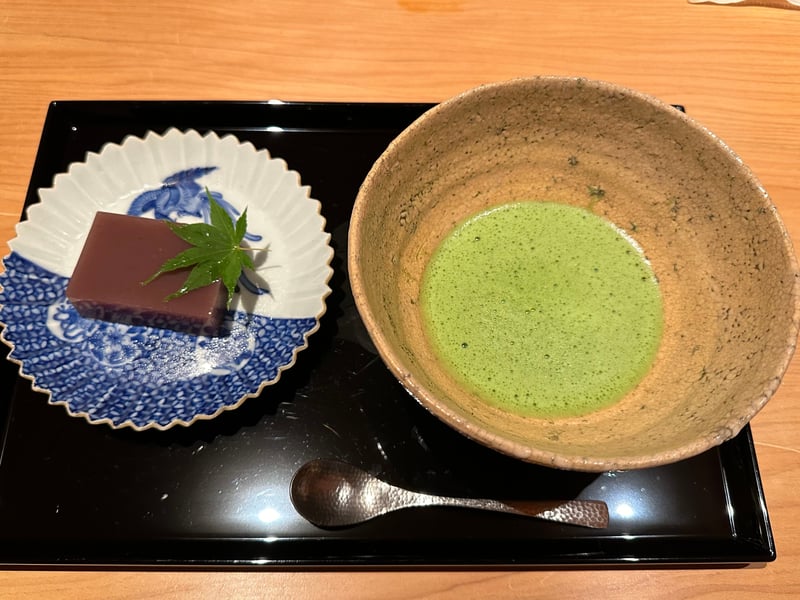 染付の皿にのった水羊羹と紅葉。隣に抹茶を点てた碗