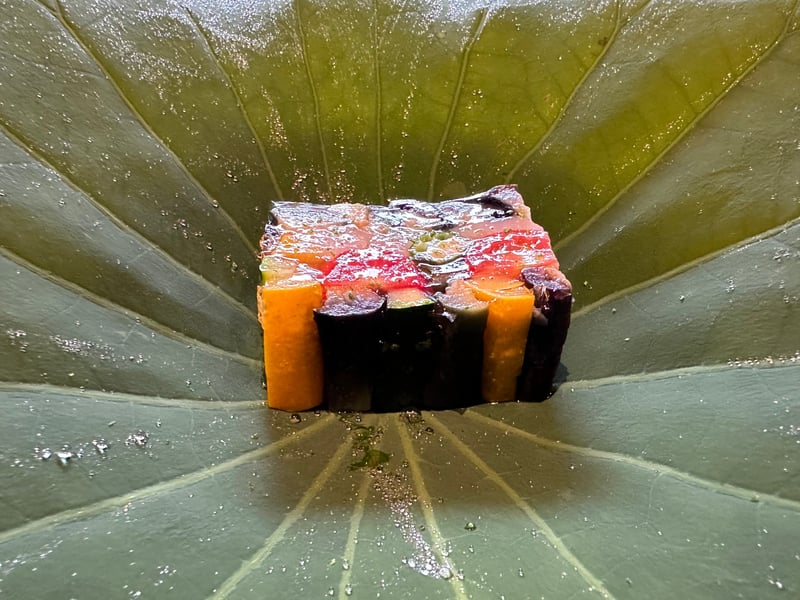 蓮の葉の上にのった夏野菜のゼリー寄せ。人参、茄子、きゅうり、トマトが層になり、白海老が見える