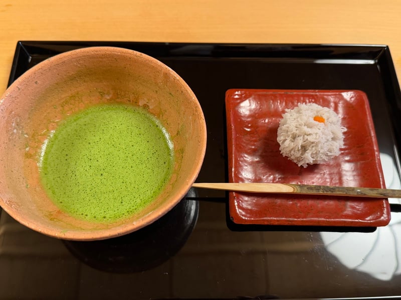 薄紅の茶碗の抹茶と、朱の角皿に和菓子の炉の火