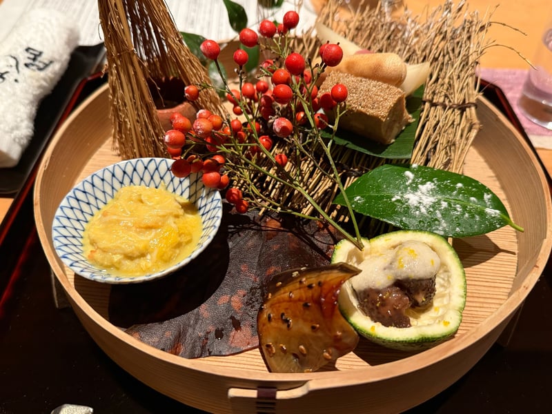 曲げわっぱに枯れ枝と南天の実を敷いた八寸。蟹の小鉢、松風と最中、ぶりの味醂干し、柚子釜のなまこが並ぶ