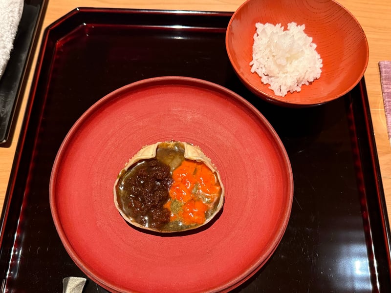 朱の皿に、内子と蟹味噌を甲羅に詰めた甲箱の醤油漬け。隣に朱の椀の銀シャリ