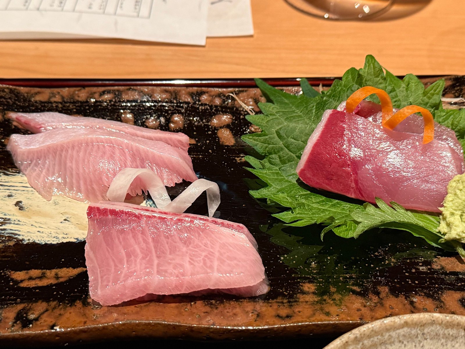 黒い長皿に、ぶりの中トロと大トロ、大葉に載せた砂ずり、わさび