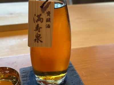 満寿泉 貴醸酒の木札が下がる、琥珀色の酒の入ったデカンタ